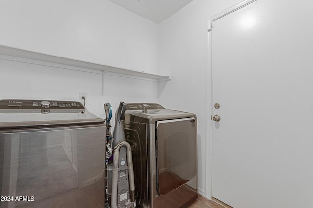 clothes washing area featuring wood finished floors, laundry area, and separate washer and dryer