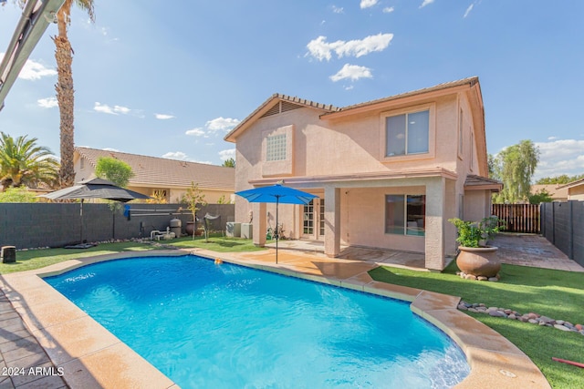 rear view of property featuring a fenced in pool, a fenced backyard, a patio, and stucco siding