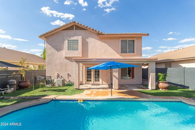 back of house with central AC, a fenced backyard, a fenced in pool, and stucco siding