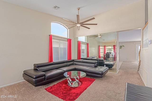 carpeted living area featuring a towering ceiling, baseboards, visible vents, and a ceiling fan