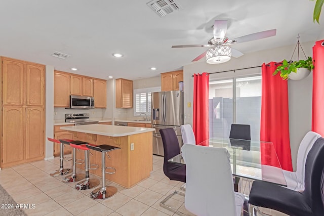 kitchen with light tile patterned floors, visible vents, a kitchen island, appliances with stainless steel finishes, and a sink