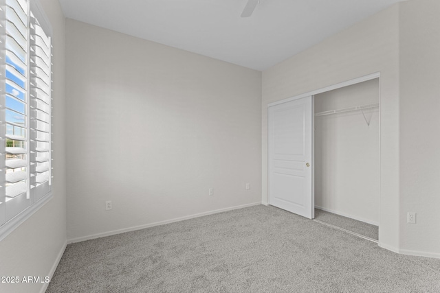 unfurnished bedroom featuring a closet, carpet floors, baseboards, and a ceiling fan