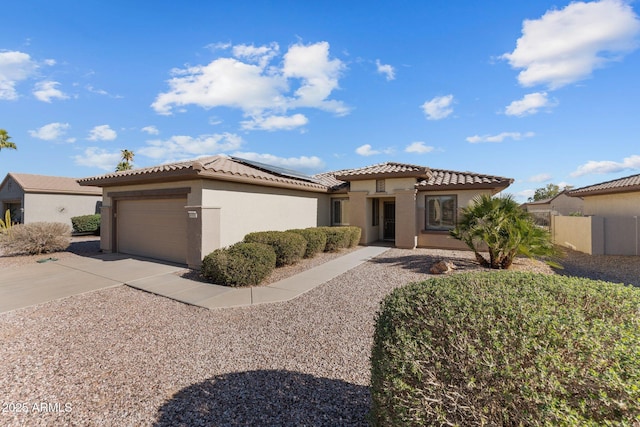 mediterranean / spanish house with solar panels, a tiled roof, an attached garage, and driveway