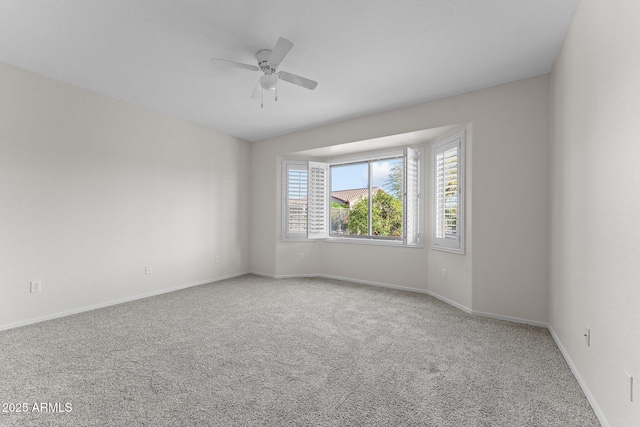 carpeted spare room with a ceiling fan and baseboards