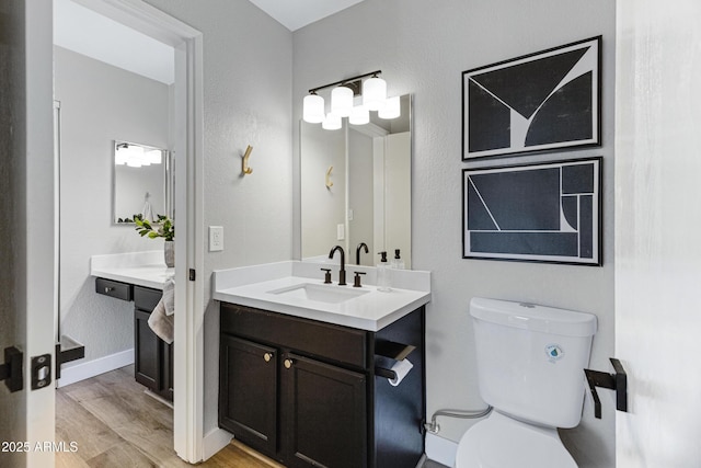 bathroom with wood finished floors, toilet, baseboards, and vanity