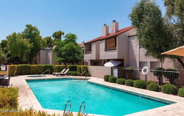 community pool with fence, a hot tub, and a patio area