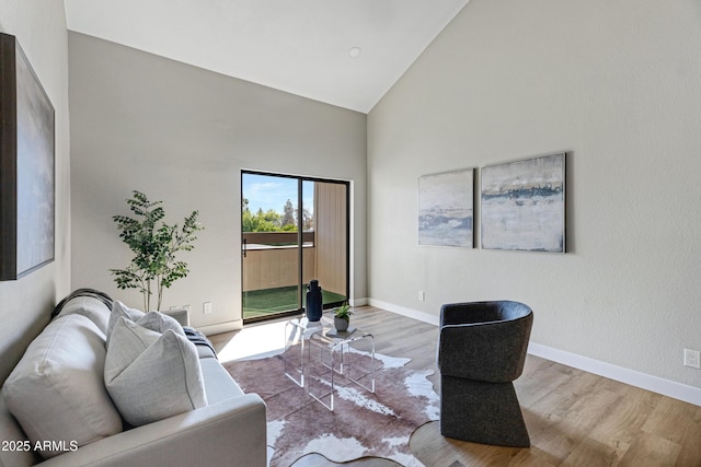 living area featuring high vaulted ceiling, wood finished floors, and baseboards