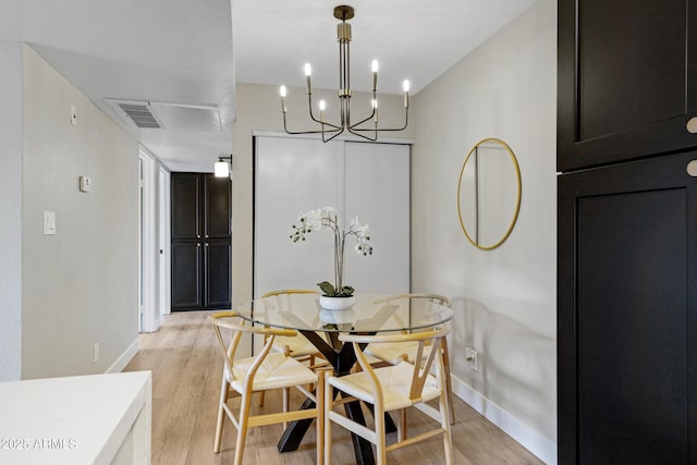 dining area featuring baseboards, light wood-type flooring, and a chandelier