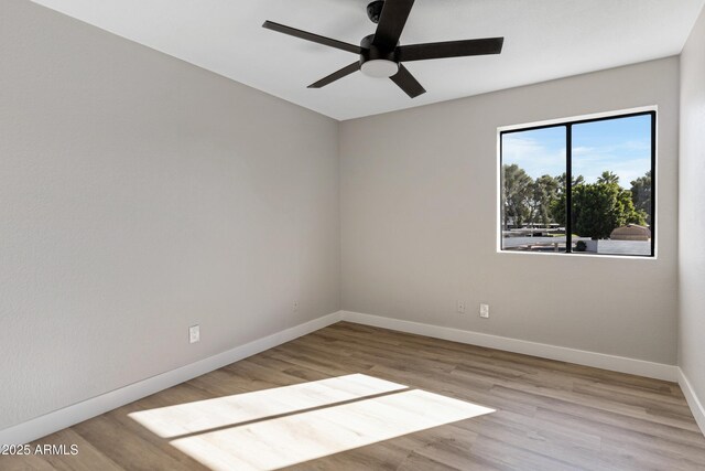 empty room with baseboards, ceiling fan, and wood finished floors