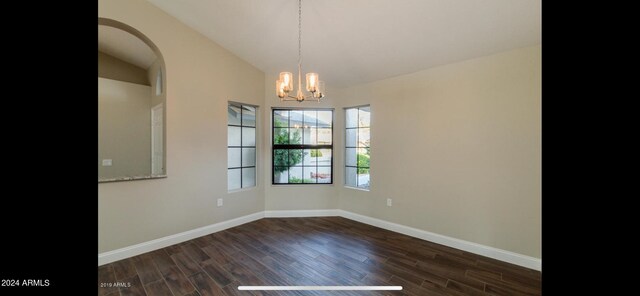 empty room featuring dark hardwood / wood-style floors, vaulted ceiling, and a chandelier