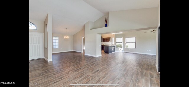 unfurnished living room featuring ceiling fan with notable chandelier, hardwood / wood-style flooring, and high vaulted ceiling