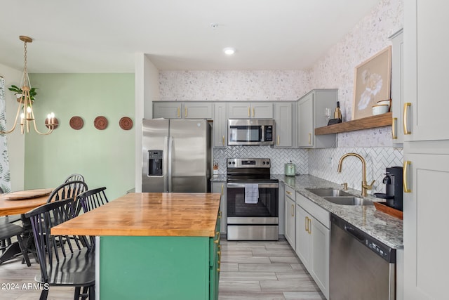 kitchen with appliances with stainless steel finishes, sink, tasteful backsplash, decorative light fixtures, and an inviting chandelier