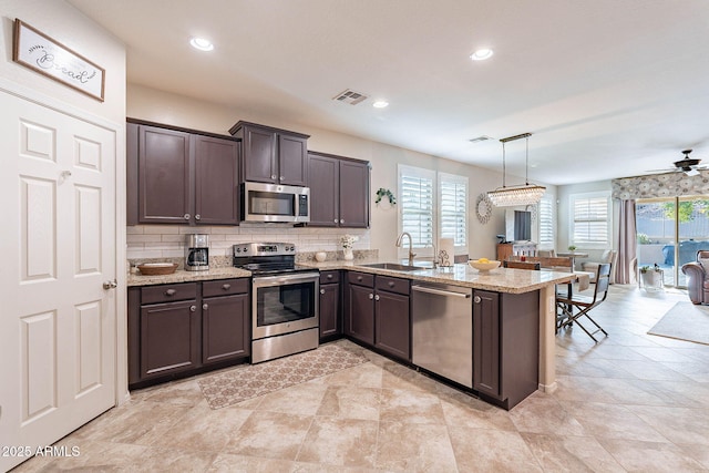 kitchen with sink, stainless steel appliances, hanging light fixtures, and kitchen peninsula