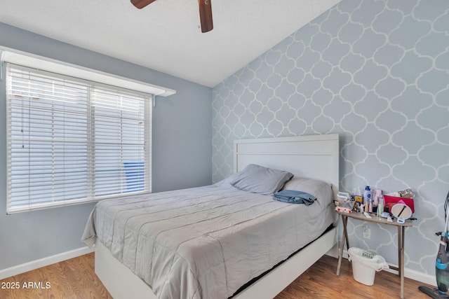 bedroom with hardwood / wood-style flooring, lofted ceiling, a textured ceiling, and ceiling fan