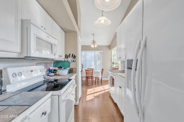 kitchen with white appliances, white cabinetry, hanging light fixtures, light hardwood / wood-style floors, and vaulted ceiling