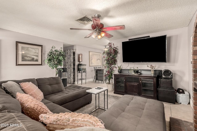 living room featuring ceiling fan, a textured ceiling, and light tile patterned flooring