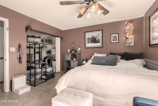 tiled bedroom featuring ceiling fan and a textured ceiling