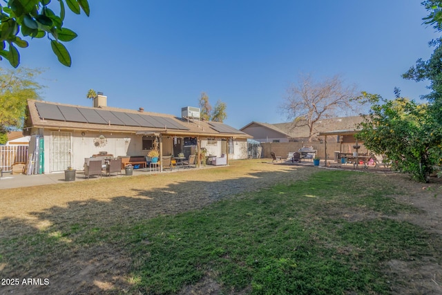 back of house with a yard, solar panels, and a patio