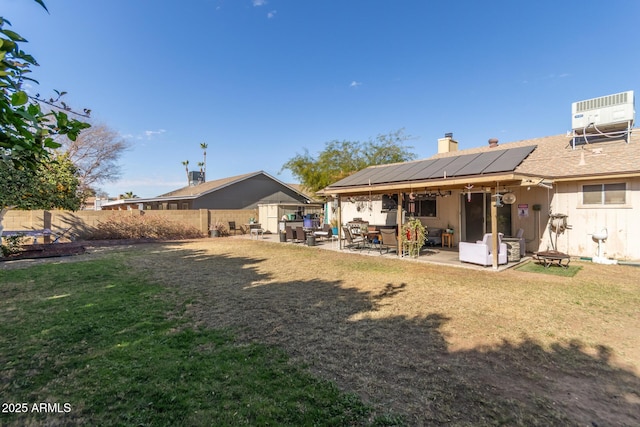 rear view of house featuring a patio area, cooling unit, a yard, and solar panels