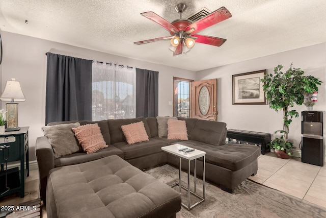 living room with a textured ceiling, ceiling fan, and light tile patterned floors