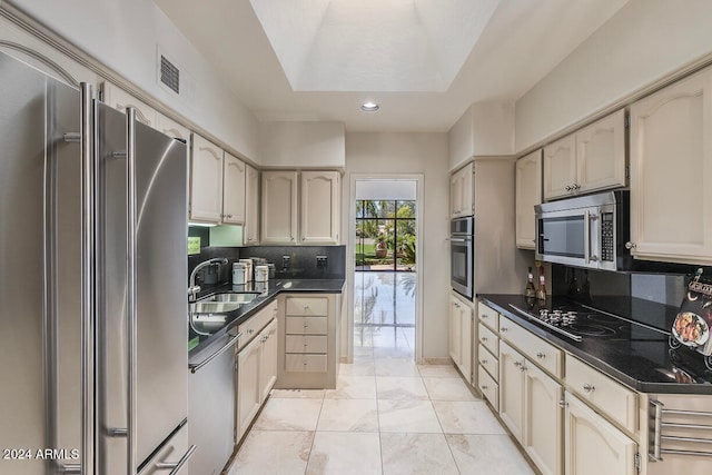 kitchen with decorative backsplash, appliances with stainless steel finishes, cream cabinetry, and sink