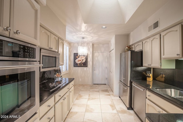 kitchen with cream cabinetry, decorative light fixtures, light tile patterned floors, and appliances with stainless steel finishes