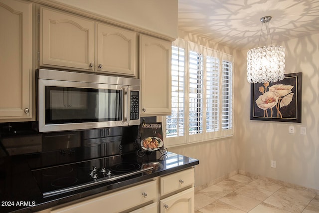 kitchen with decorative light fixtures, black cooktop, a healthy amount of sunlight, and a notable chandelier