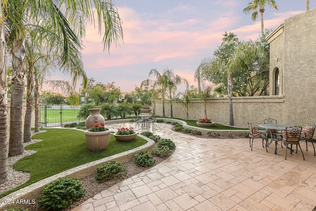 patio terrace at dusk featuring a lawn