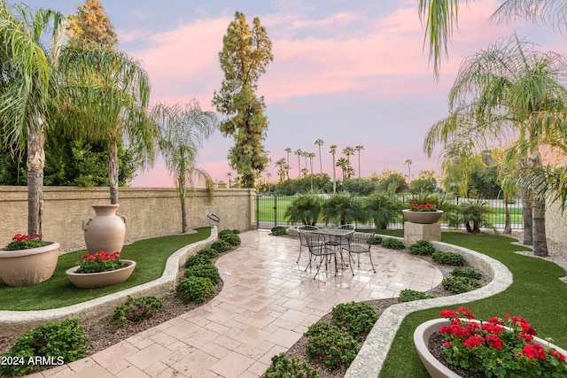 patio terrace at dusk featuring a yard