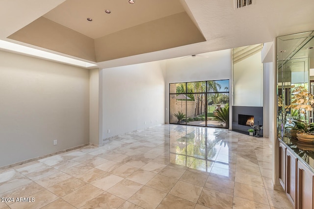 unfurnished living room featuring a raised ceiling and ceiling fan