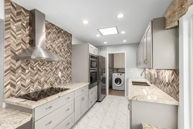 kitchen with black electric stovetop, sink, wall chimney range hood, washer / dryer, and oven