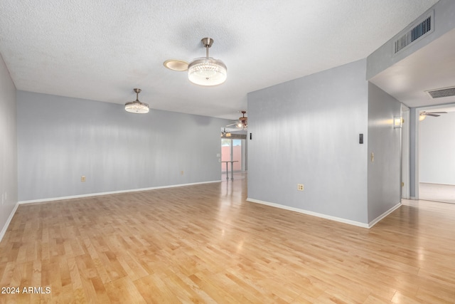 empty room with ceiling fan, light hardwood / wood-style floors, and a textured ceiling