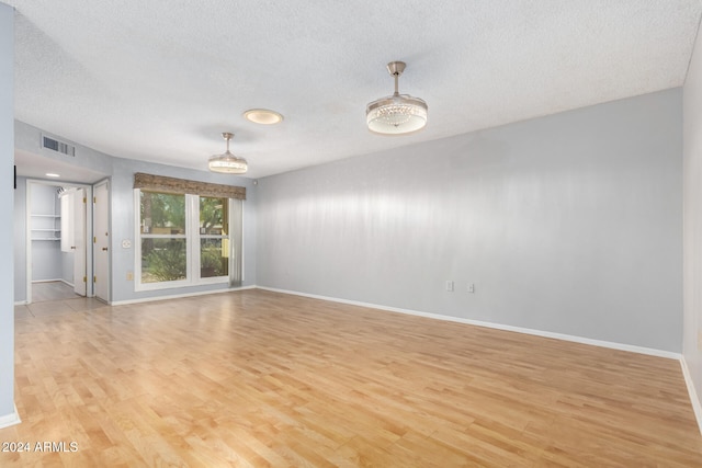 spare room with a textured ceiling and light hardwood / wood-style flooring