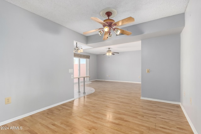 unfurnished room with ceiling fan with notable chandelier, a textured ceiling, and light hardwood / wood-style flooring