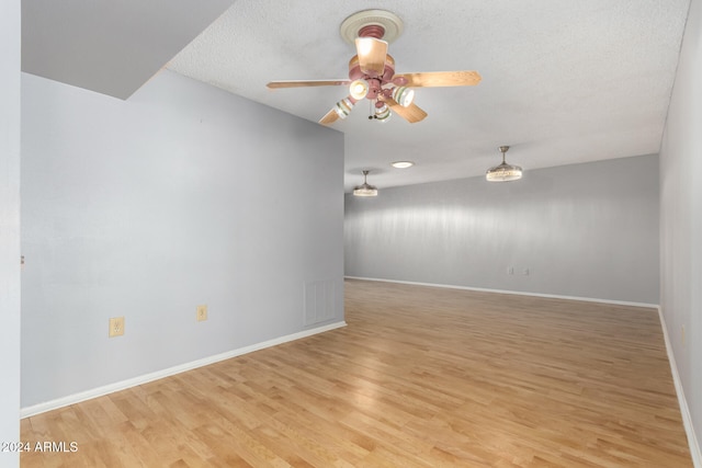 spare room with a textured ceiling, light hardwood / wood-style flooring, and ceiling fan