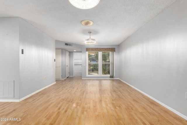 unfurnished room featuring a textured ceiling and light hardwood / wood-style flooring