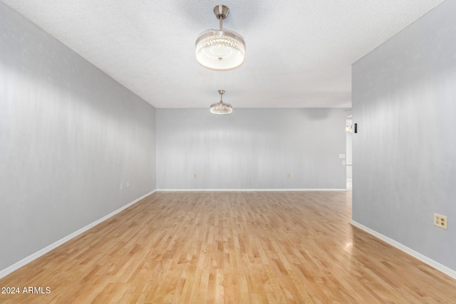 unfurnished room with a textured ceiling and light hardwood / wood-style floors