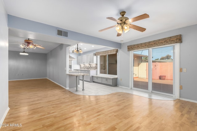 unfurnished living room with light hardwood / wood-style floors and ceiling fan with notable chandelier