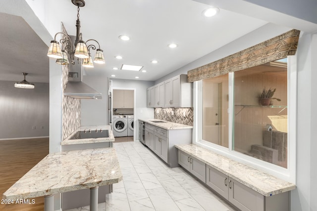 kitchen featuring pendant lighting, backsplash, black electric stovetop, gray cabinets, and washing machine and dryer