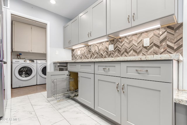 clothes washing area with washer and clothes dryer and cabinets