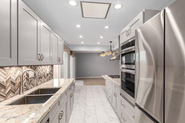 kitchen featuring stainless steel fridge, backsplash, light stone counters, sink, and gray cabinets