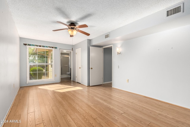 empty room with a textured ceiling, light hardwood / wood-style floors, and ceiling fan