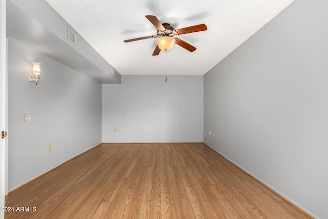 unfurnished room with ceiling fan, a textured ceiling, and light wood-type flooring