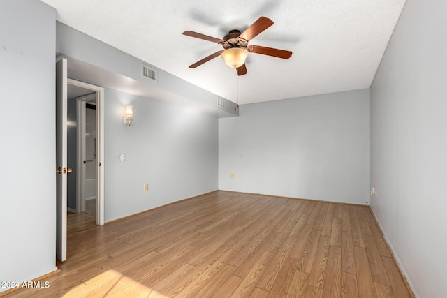 spare room with a textured ceiling, light wood-type flooring, and ceiling fan