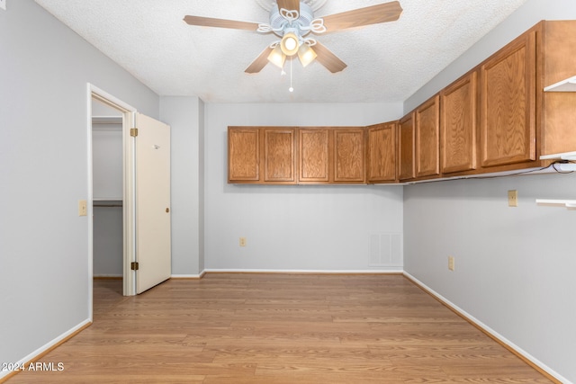 interior space with a textured ceiling, light wood-type flooring, and ceiling fan