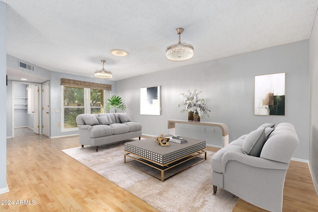 living room with a textured ceiling and light wood-type flooring