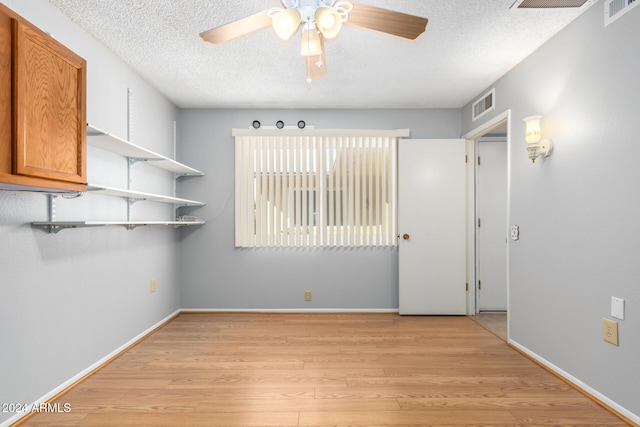 unfurnished room with ceiling fan, light hardwood / wood-style flooring, and a textured ceiling