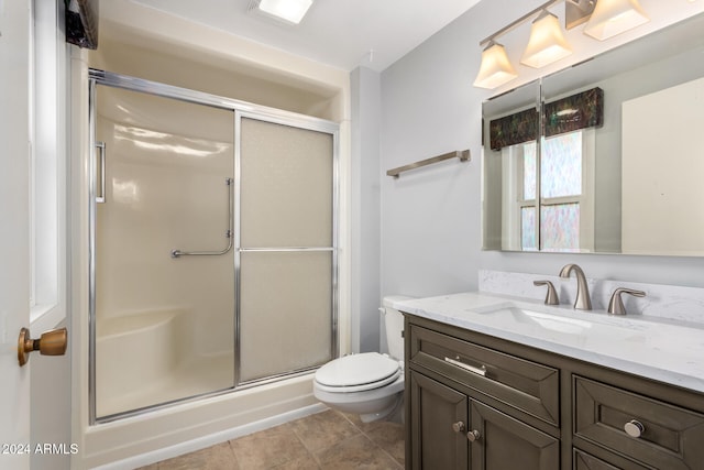 bathroom featuring toilet, vanity, tile patterned floors, and an enclosed shower