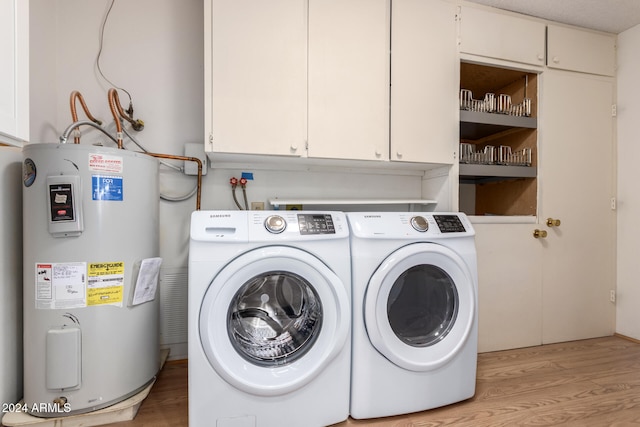 laundry area with washing machine and clothes dryer, cabinets, water heater, light hardwood / wood-style flooring, and a textured ceiling