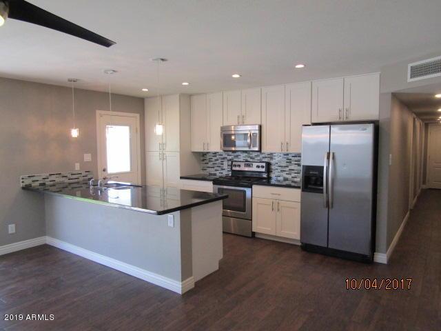 327 E Ln Jolla Dr, Tempe, AZ 85282 - kitchen featuring appliances with stainless steel finishes, dark wood-style flooring, tasteful backsplash, dark countertops, and white cabinetry